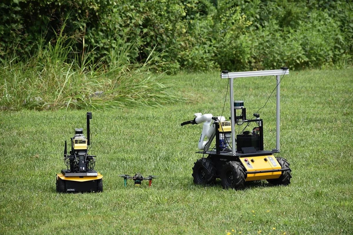 NASA:s ASTRA-flotta med två markrobotar och en drönare under ett fälttest på en gräsyta.