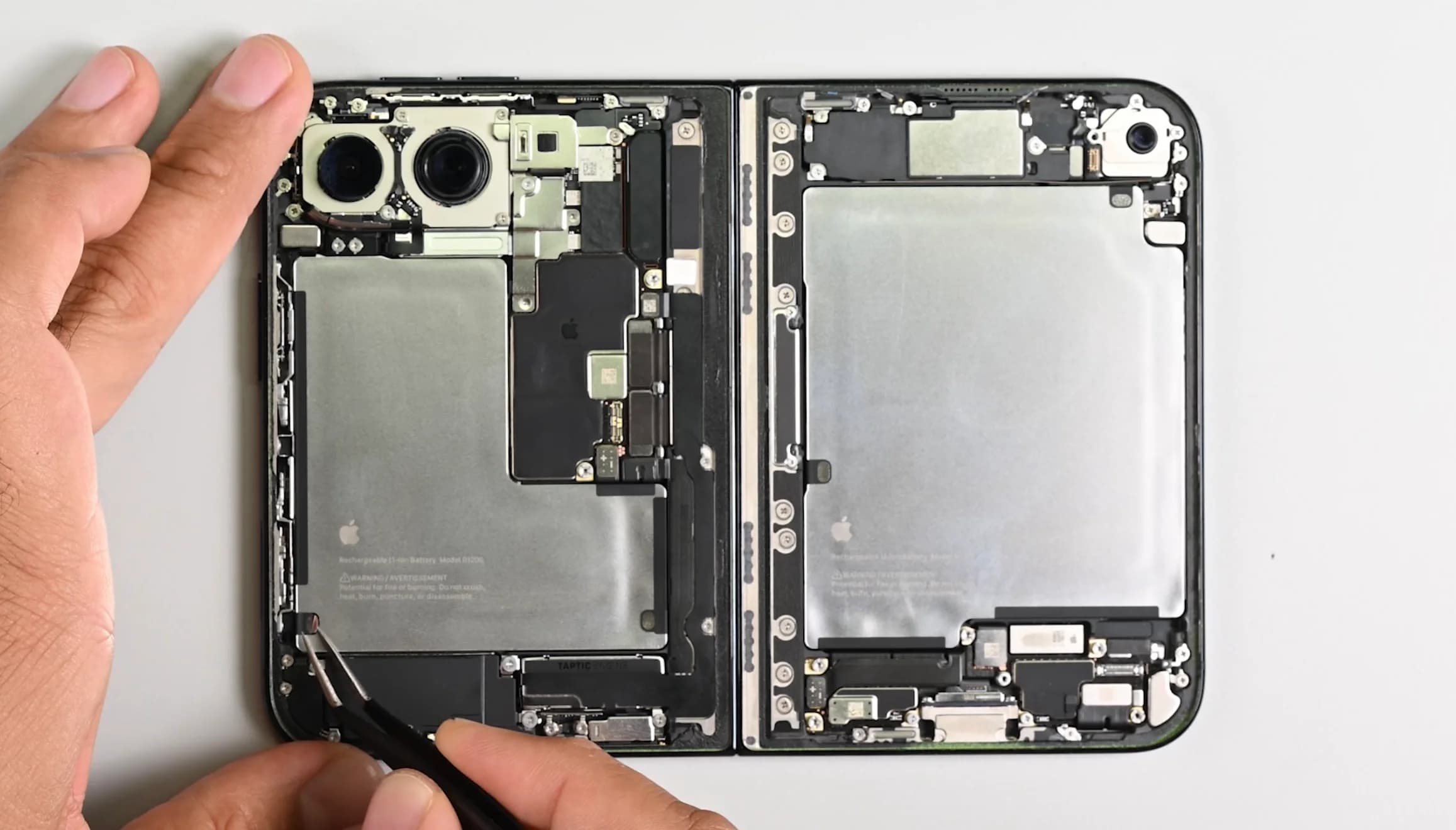 En demonterad iPhone Duo med synliga batterier, kameror och gångjärn under iFixits genomgång.