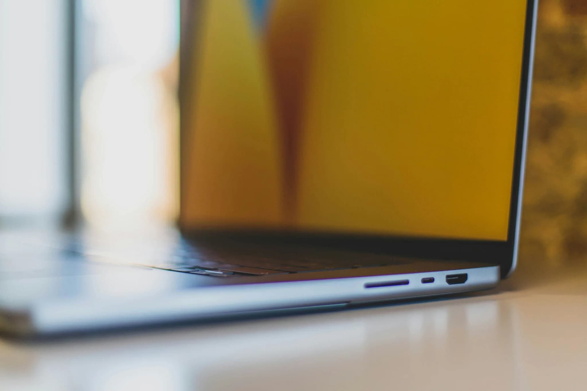 Närbild från sidan av en delvis öppen MacBook Pro på ett bord, med anslutningarna synliga.
