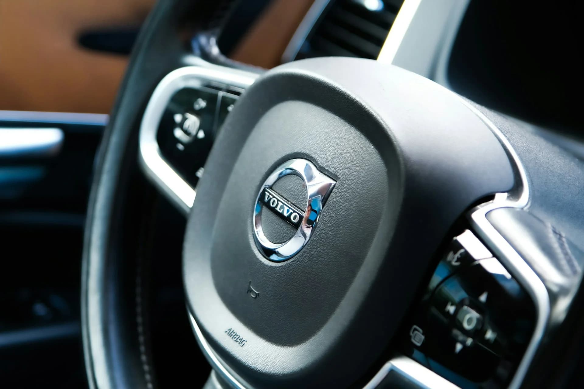 Närbild av ratten i en Volvo med företagets emblem i centrum.
