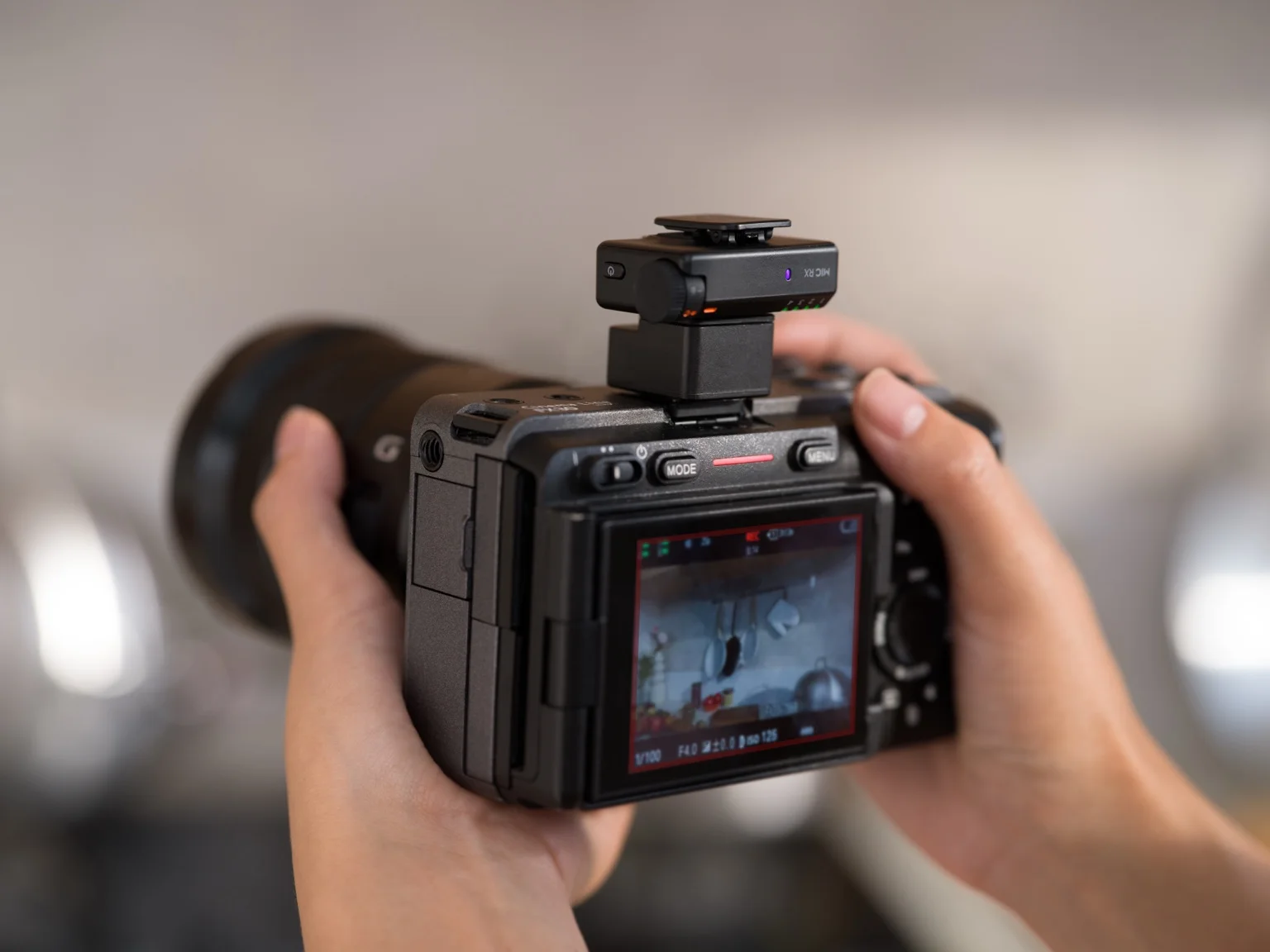 DJI Mic Mini 2S-mottagare monterad ovanpå en kamera som hålls i händerna.