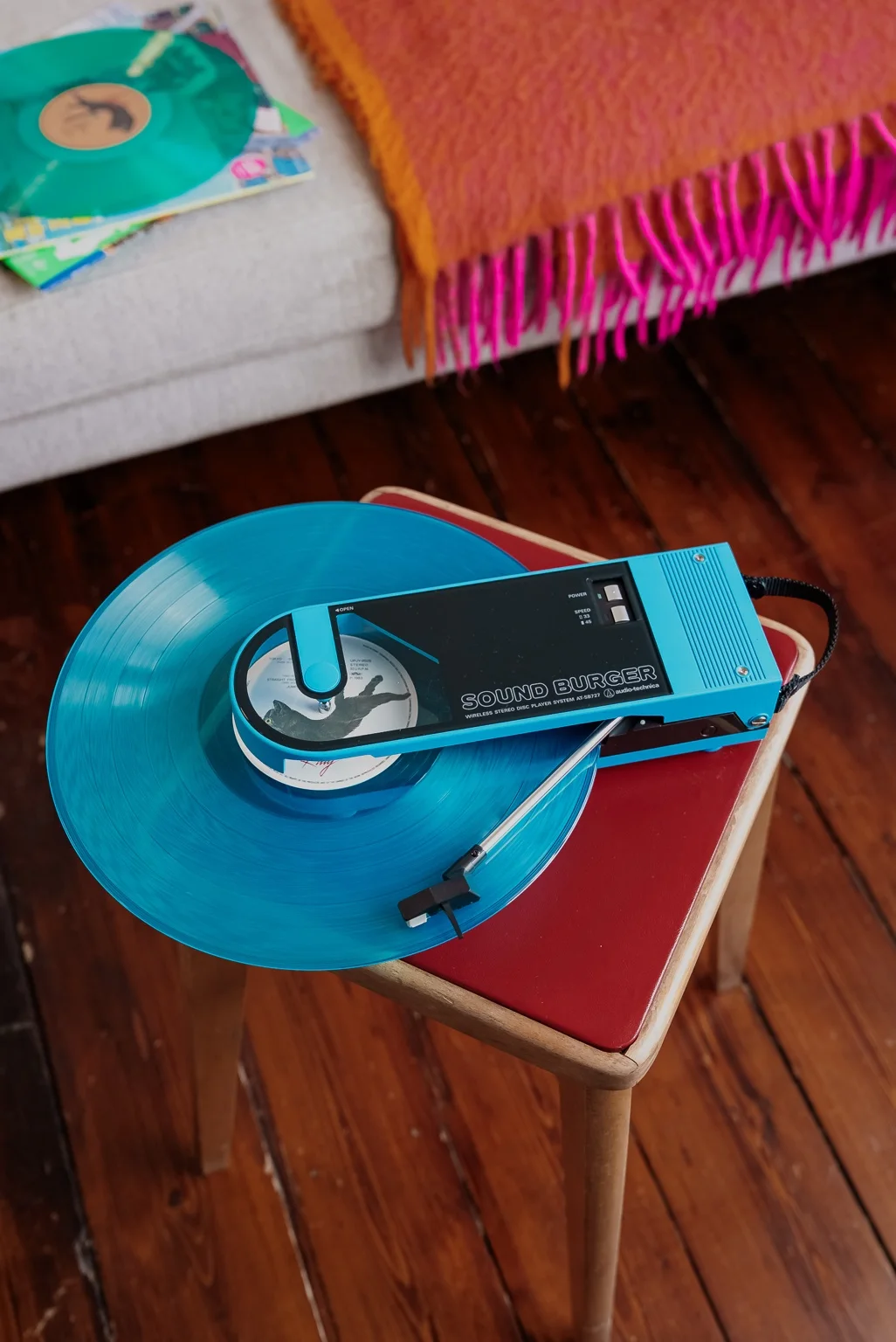 Blå Sound Burger spelar en blå vinylskiva på en stol